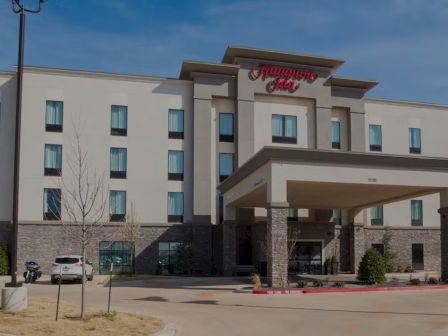 A Hilton Garden Inn-style hotel with a beige facade, a covered entrance, and a sign reading &ldquo;Flamingo Inn&rdquo; above the canopy.